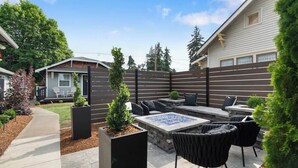 Un patio con mobiliario exterior, una chimenea y una mesa de piedra.