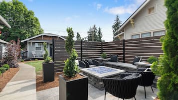 A patio area with outdoor furniture, a fire pit, and a wooden fence.