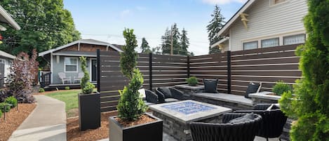 A patio area with outdoor furniture, a fire pit, and a wooden fence.