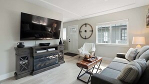 Una sala de estar con una televisión de pantalla plana, un sofá, una mesa de centro y una chimenea.