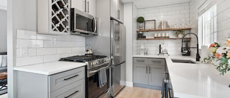 A modern kitchen with white cabinetry, stainless steel appliances, and a wine rack.