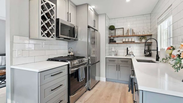 Una cocina moderna con armarios blancos, electrodomésticos de acero inoxidable y encimera blanca.