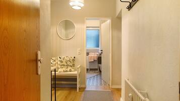 A hallway with a wooden door, a radiator, a patterned bench, a mirror, and a patterned floor.