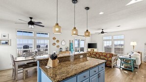 Une cuisine spacieuse dotée de plans de travail en granit, de meubles bleus et de luminaires suspendus.