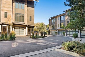 Un immeuble résidentiel moderne doté d’une allée incurvée, de portes de garage et d’espaces paysagers aménagés.
