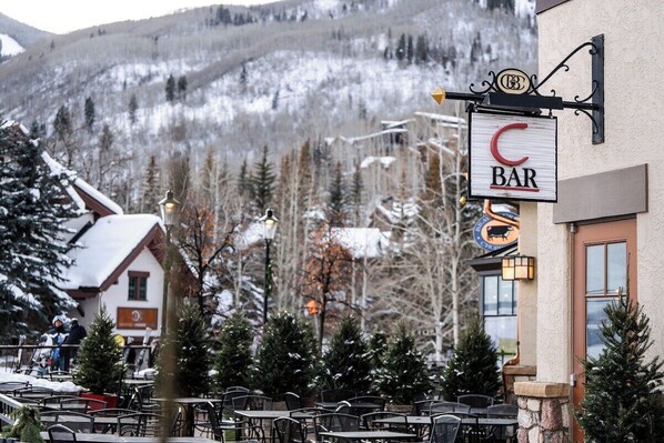 Un bar avec une terrasse, une vue sur les montagnes en arrière-plan et une enseigne indiquant qu’il s’agit d’un restaurant.