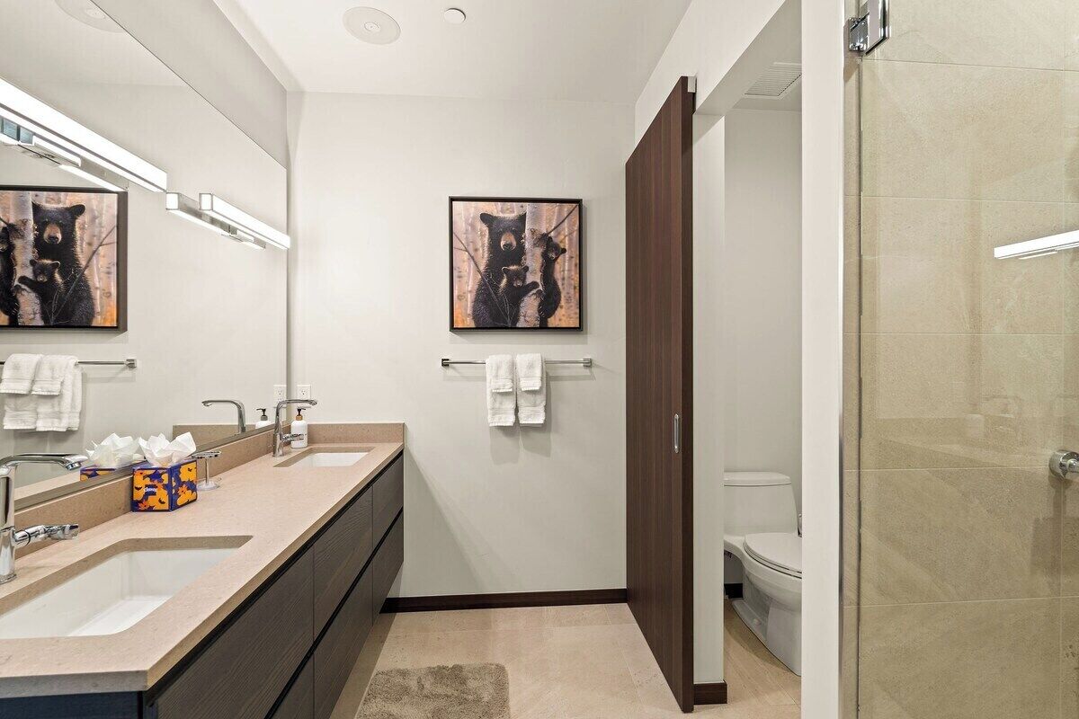 Ein modernes Badezimmer mit zwei Waschbecken, einem großen Spiegel und einem gerahmten Kunstwerk darüber.