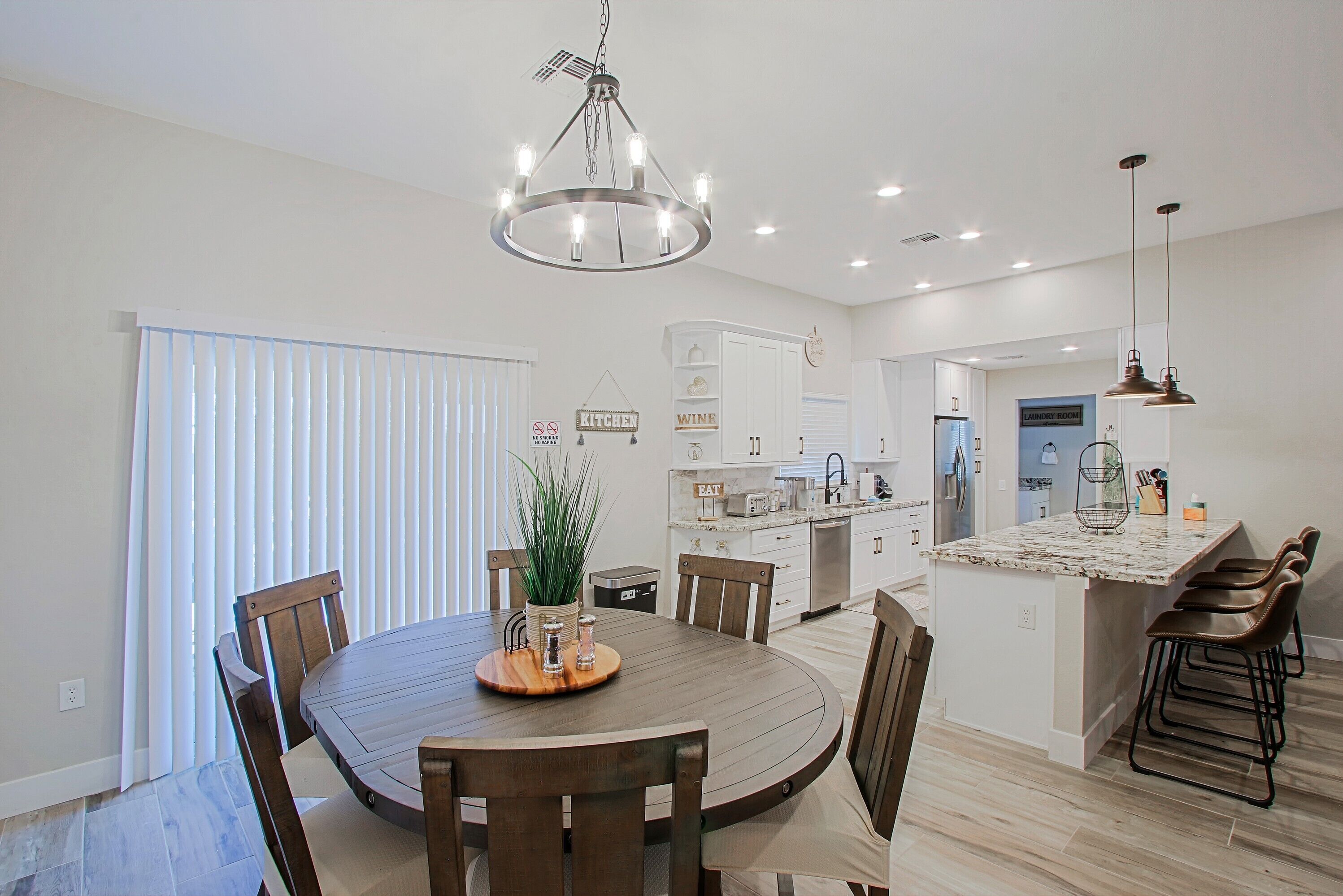 A modern kitchen with a central island, wooden dining table, and chairs.