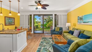 A modern living room with a kitchen, a ceiling fan, and a view of the outdoors. - Kiahuna Paradise @ Poipu with 2  AC units 
Family size condo with patio (Koloa)