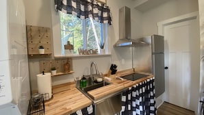 Een keuken met houten aanrechtbladen, een roestvrijstalen spoelbak, een inbouwoven en een koelkast.