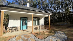 Een gelijkvloers huis met een blauwe deur, een overdekte veranda en een pad van stenen dat naar de ingang leidt.