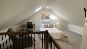 Een knus zolderkamer met een bed, een bureau en een stoel.