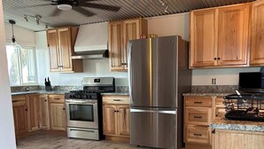 A kitchen with wooden cabinets, stainless steel appliances, a tiled floor, and a ceiling fan. - Mucho Gusto PLUS Casita: 3br 3ba, 2.4 miles from BBNP (Terlingua)