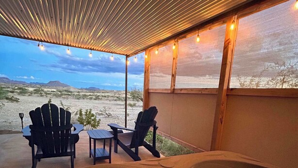 A hot tub with two Adirondack chairs, a table, and a view of a desert landscape. - Mucho Gusto PLUS Casita: 3br 3ba, 2.4 miles from BBNP (Terlingua)