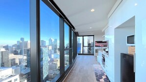 A modern apartment with large windows offering a city view, a kitchen area, and a living space. - LV42 High-Rise Condo CBD Panoramic City View (Melbourne)