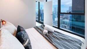 A hotel room with a large bed, a city view through the window, and a modern design. - LV42 High-Rise Condo CBD Panoramic City View (Melbourne)