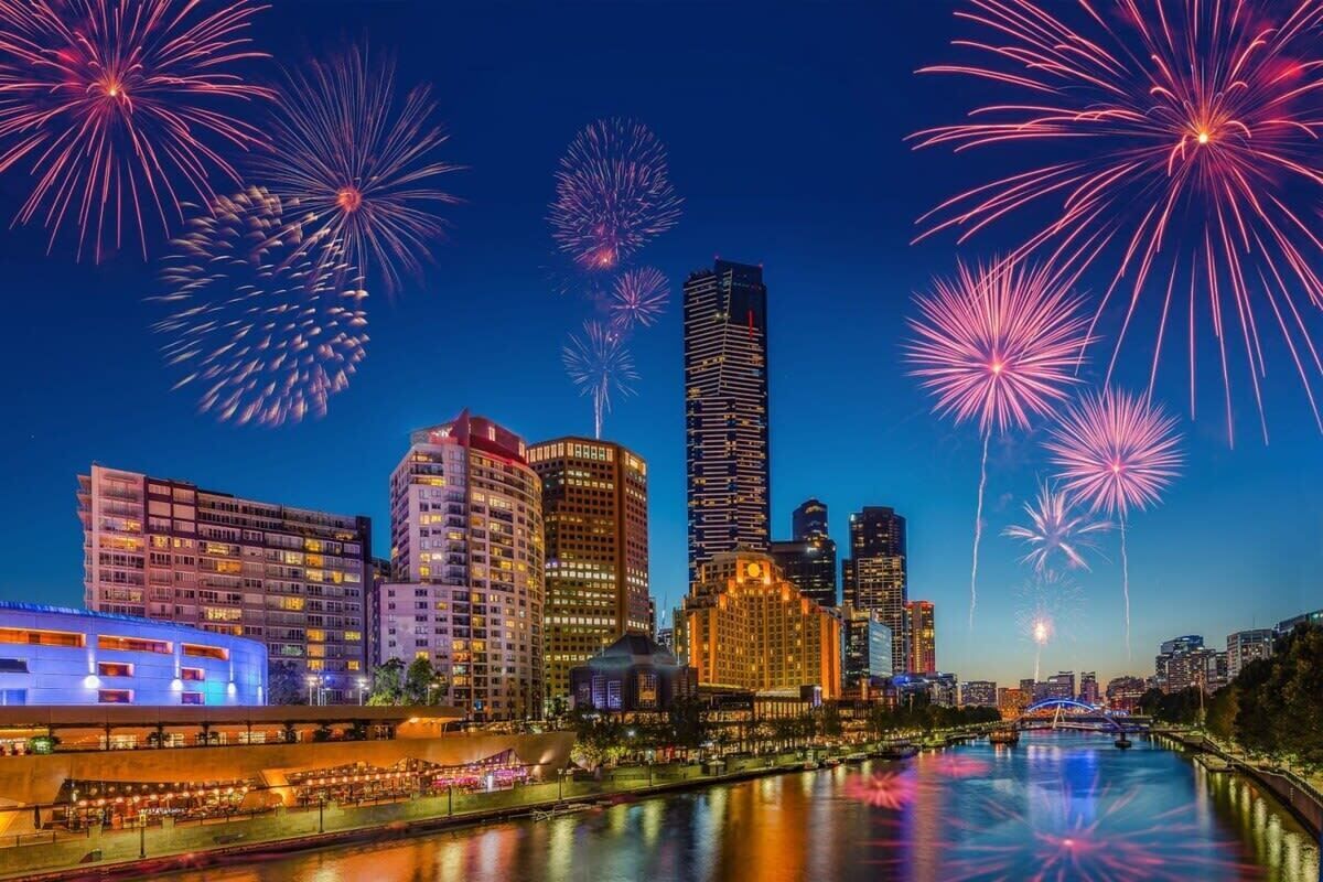 A cityscape with a river, buildings, and fireworks.