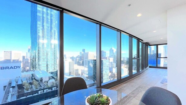 A modern office space with large windows offering a city view. - LV42 High-Rise Condo CBD Panoramic City View (Melbourne)