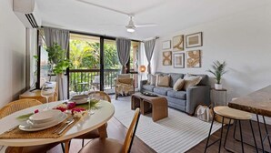 Un salon moderne avec un coin repas, un canapé gris et un balcon agrémenté de plantes.