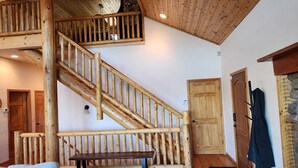 Un escalier en bois, avec un banc en bas, une porte et un porte-manteau.