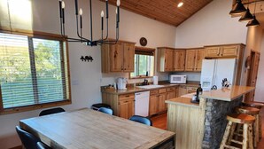 Une cuisine moderne avec des meubles en bois, un îlot central et un coin repas comprenant une grande table et des chaises.