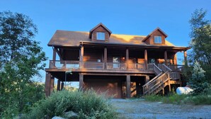 Une cabane en rondins à deux étages, dotée d’un balcon et d’un escalier menant à l’étage supérieur.
