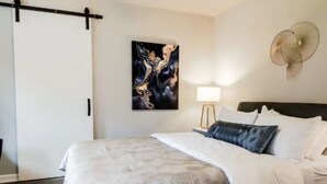 Ein Hotelzimmer mit Bett, Wandbild, Stehlampe und Deckenventilator.
