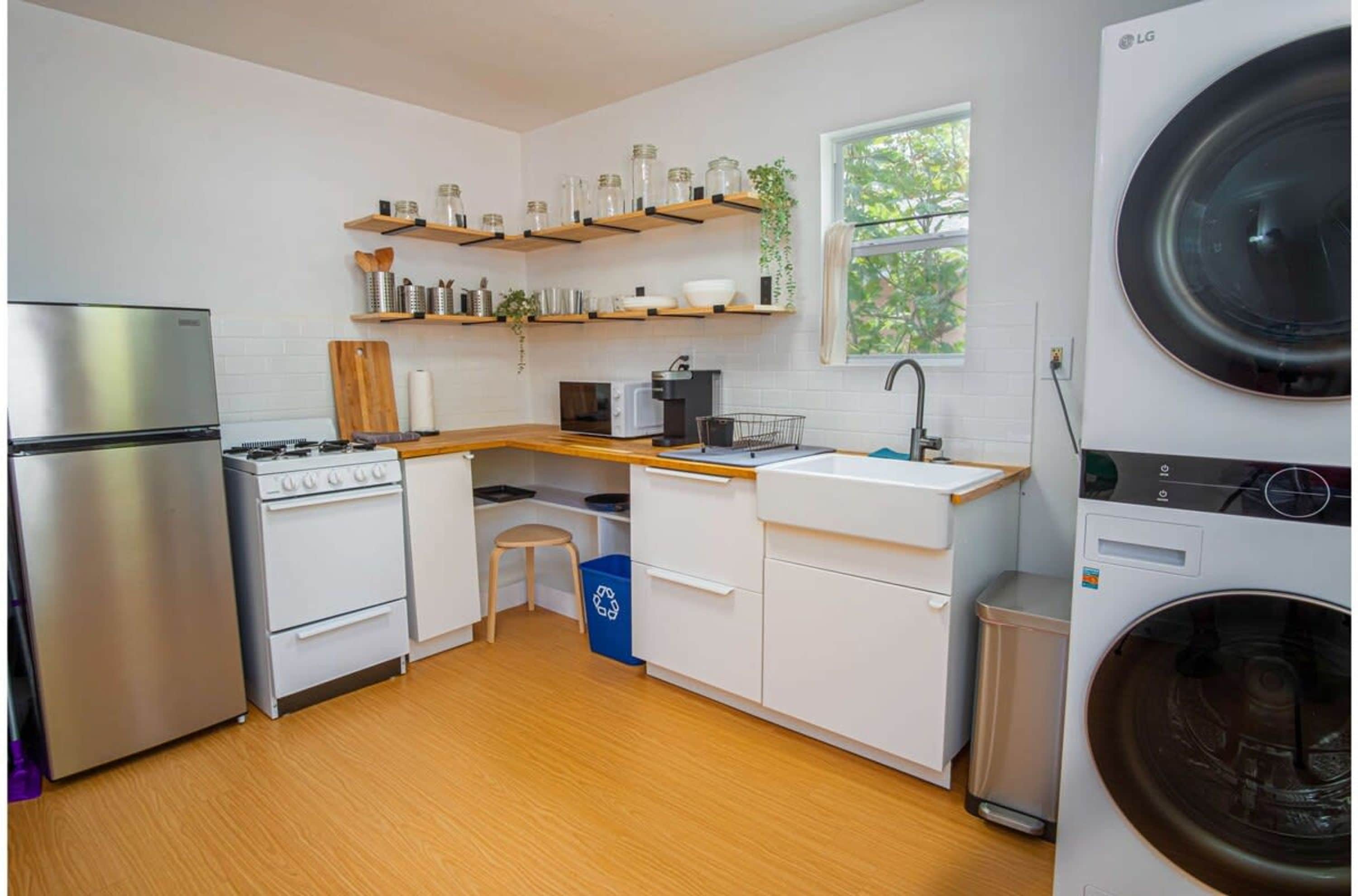Eine kompakte Küche mit Kühlschrank, Herd, Mikrowelle und Waschmaschine.