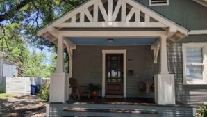 A two-story house with a front porch, a door, and a small garden area. - Chic Downtown Farmhouse With Garden and BBQ Grill (San Antonio)