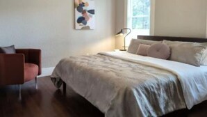 A bedroom with a bed, a chair, a window, and a wall-mounted artwork. - Chic Downtown Farmhouse With Garden and BBQ Grill (San Antonio)