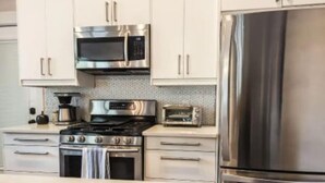 A modern kitchen with stainless steel appliances, including a microwave, oven, and refrigerator. - Chic Downtown Farmhouse With Garden and BBQ Grill (San Antonio)