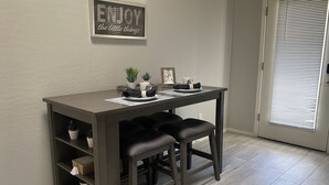 A dining area with a table, two chairs, a shelf with decorative items, and a wall sign. - Super close to all the fun, short walk to Westgate Entertainment District.   (Glendale)