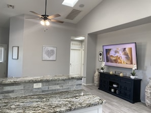 A kitchen with granite countertops, a black cabinet, and a ceiling fan.