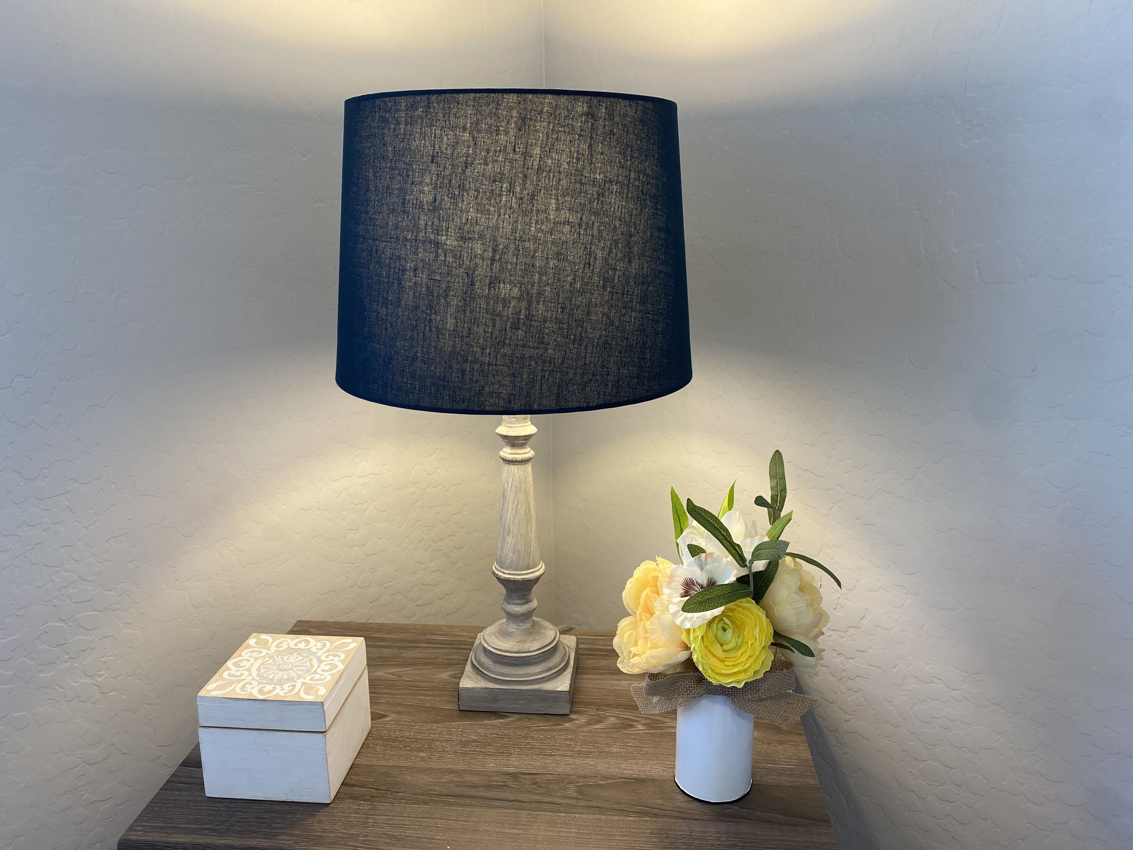 Ein Tisch mit einer Lampe, einer dekorativen Schachtel und einer Blumenvase.