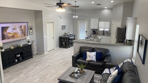 A modern living room with a flat-screen TV, a dark leather sofa, a coffee table, and a ceiling fan. - Super close to all the fun, short walk to Westgate Entertainment District.   (Glendale)