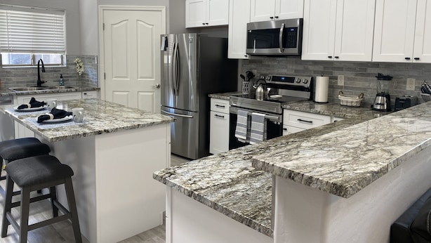 A modern kitchen with white cabinets, stainless steel appliances, and granite countertops. - Super close to all the fun, short walk to Westgate Entertainment District.   (Glendale)
