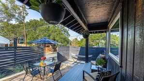 An outdoor patio with a table, chairs, and a hanging planter.