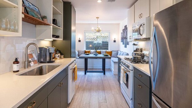 A modern kitchen with a central island, stainless steel appliances, and a built-in oven.