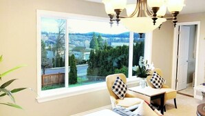 Ein Zimmer mit einem großen Fenster, einem Essbereich mit Tisch und Stühlen sowie einer Chandeliebre.