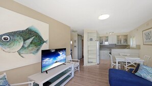 A living room with a flat-screen TV, a sofa, and a fish painting on the wall.