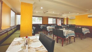 Un restaurante con varias mesas dispuestas para comer, con una decoración clásica que incluye paredes amarillas y detalles de madera.