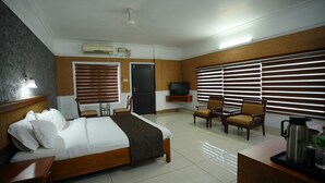 Una habitación de hotel con cama, escritorio, silla, televisor y cafetera.
