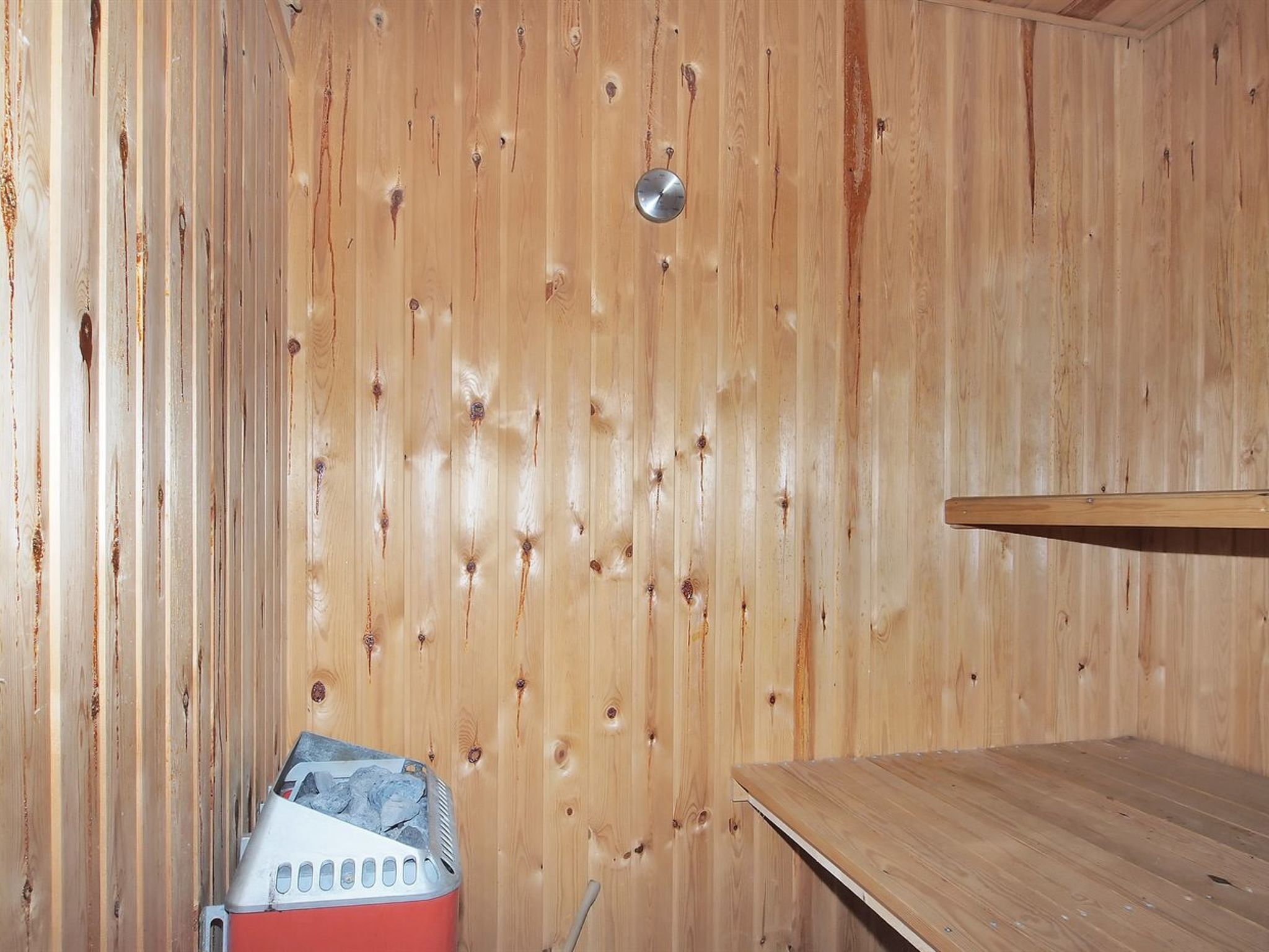 L’intérieur d’un chalet en bois comprend un sauna, un banc en bois et un appareil de chauffage pour sauna.