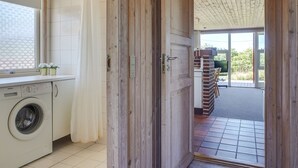 A modern kitchen with a washing machine, wooden door, and a view of the outdoor patio area.