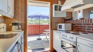 A compact kitchen with a wooden interior, a microwave, a stove, and a coffee maker.