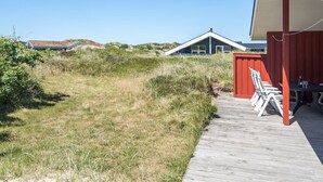 A wooden deck leading to a building with a red exterior and a white roof.