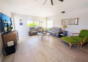 A spacious living room with a sofa set, a coffee table, a television, and a sign that reads 'BEACHHOUSE'. - Beautiful Canal front Home with Above Ground Pool, Dock and Fish Cleaning Station (Key Largo)