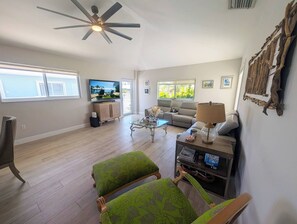 A living room with a television, sofa, coffee table, and chairs.