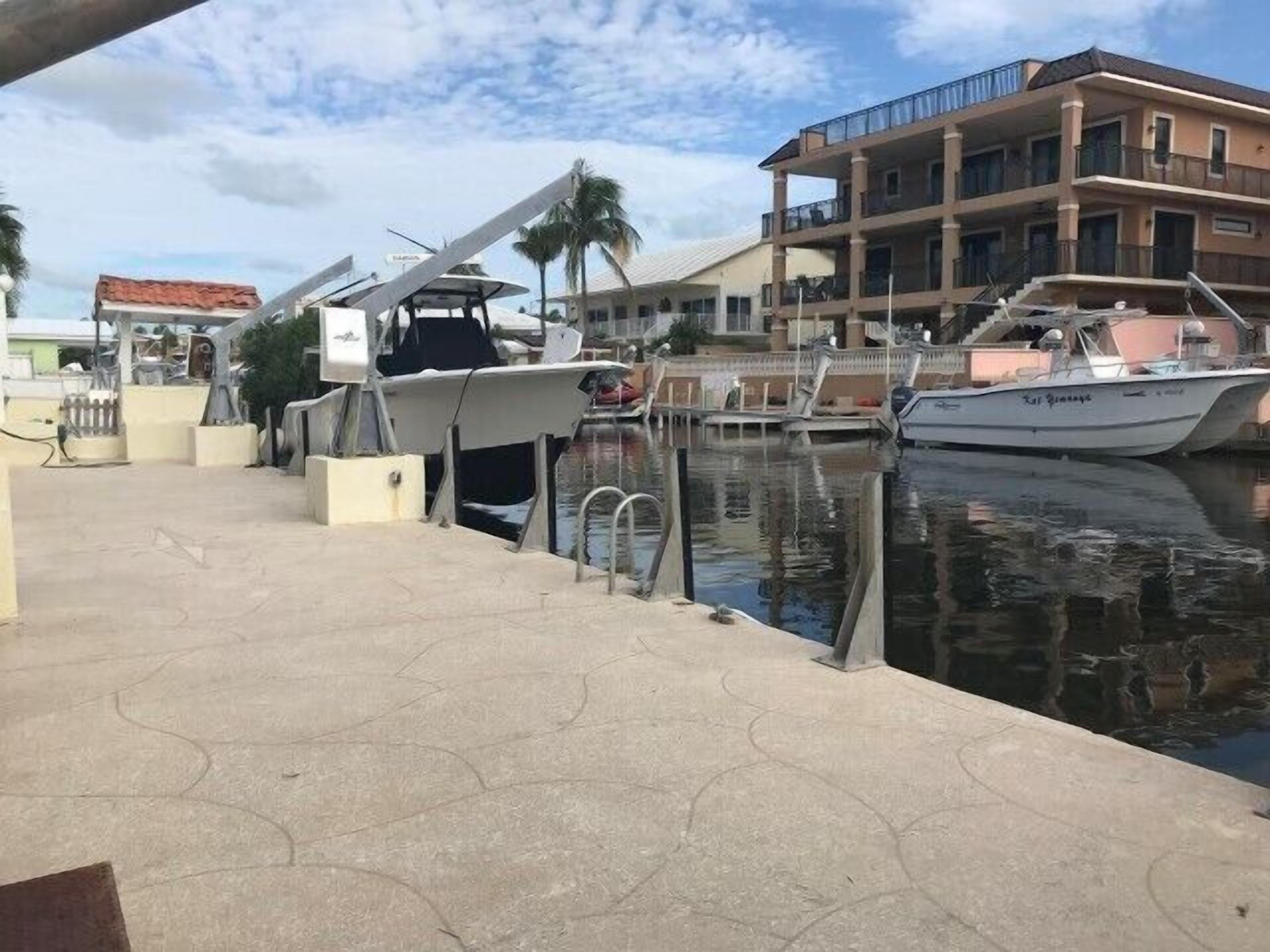 Een jachthaven met aangemeerde boten, een gebouw met balkons en een heldere lucht.