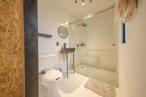 Un baño moderno con ducha de mampara de vidrio, inodoro y lavamanos.